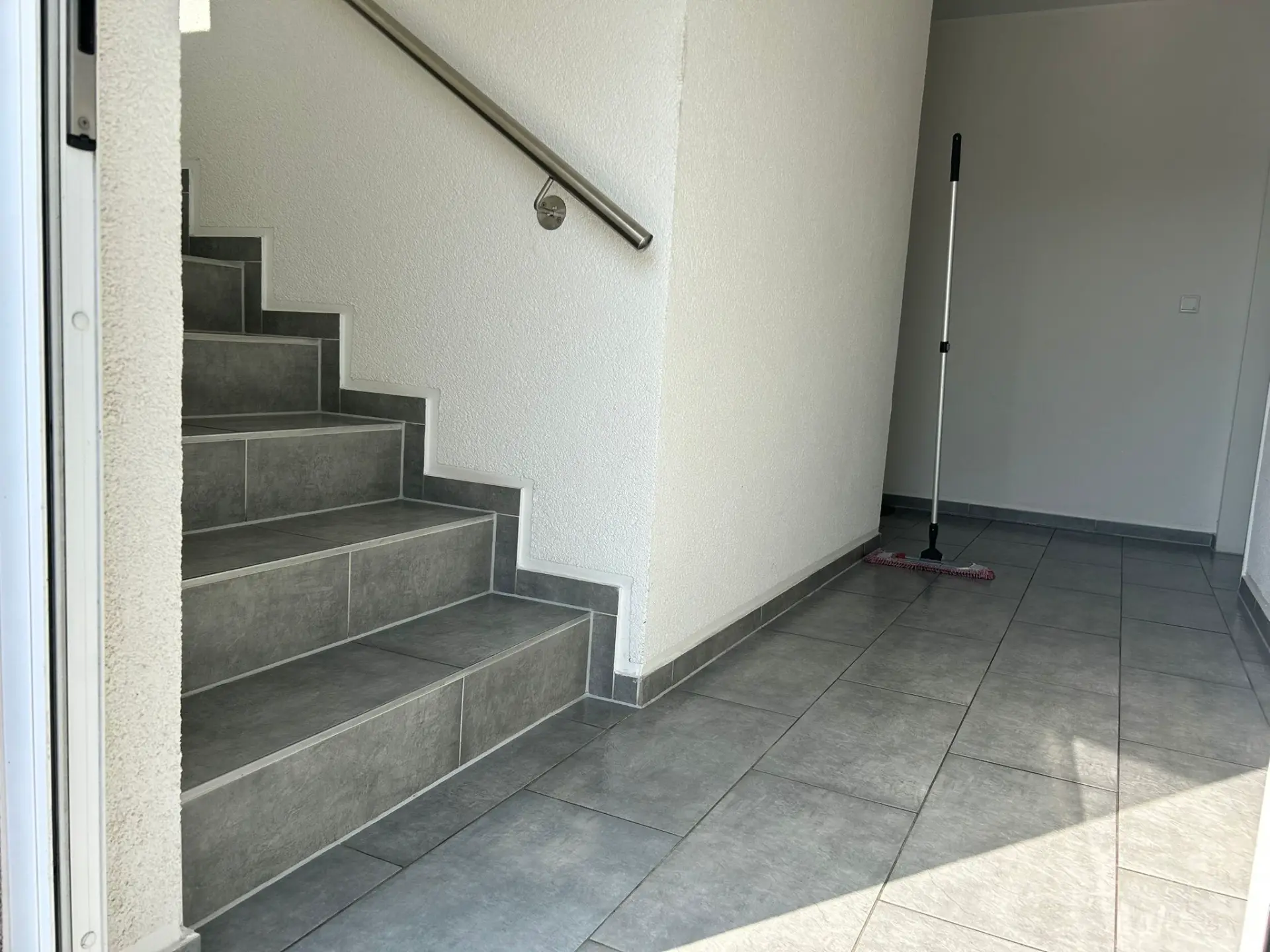 Gereinigtes Treppenhaus mit Fliesenboden und Mop in Essen